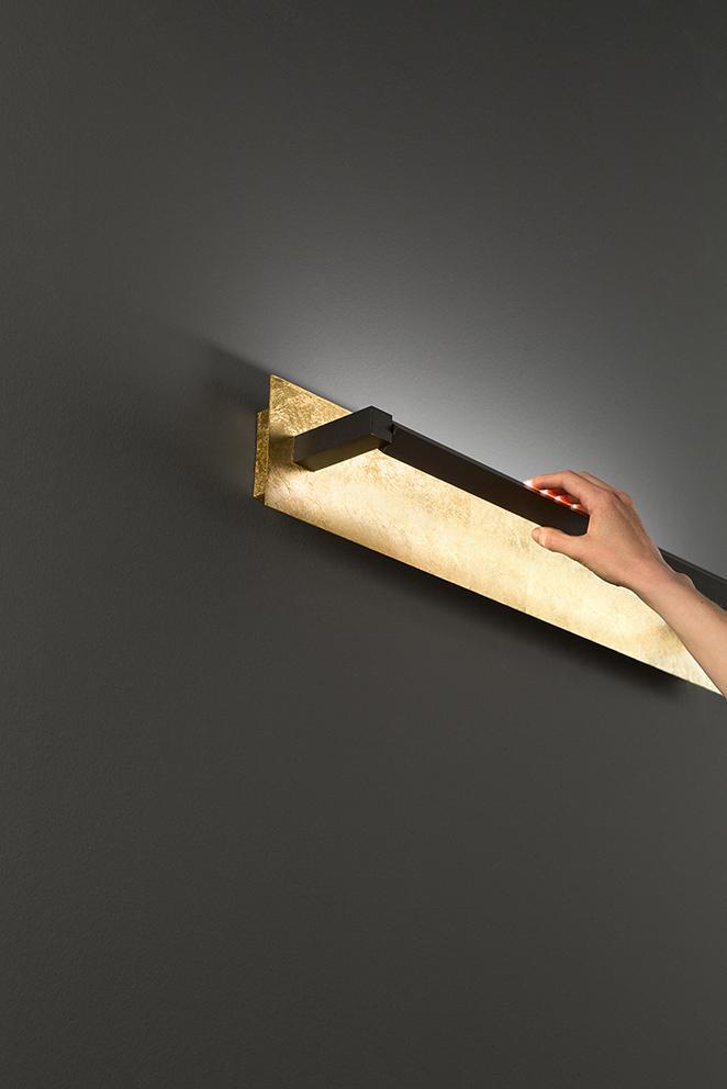applique da parete in metallo finitura foglia oro design moderno di Perenz installata su parete scura