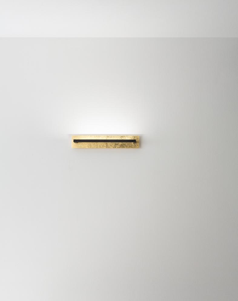 applique moderna in metallo foglia oro Perenz ambientata su parete chiara luce accesa
