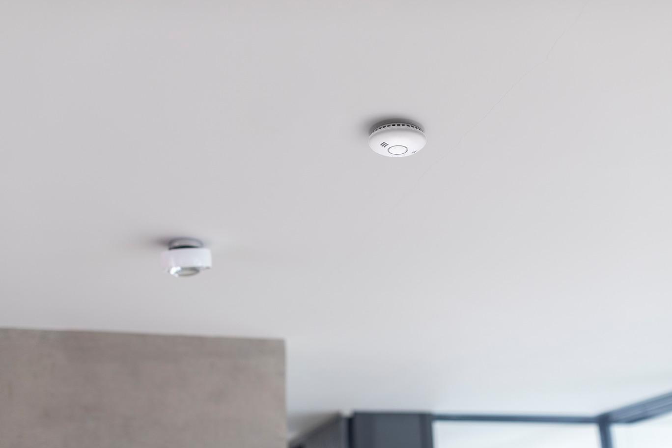 Rilevatori di fumo e calore WiFi installati a soffitto in ambiente moderno per sicurezza intelligente
