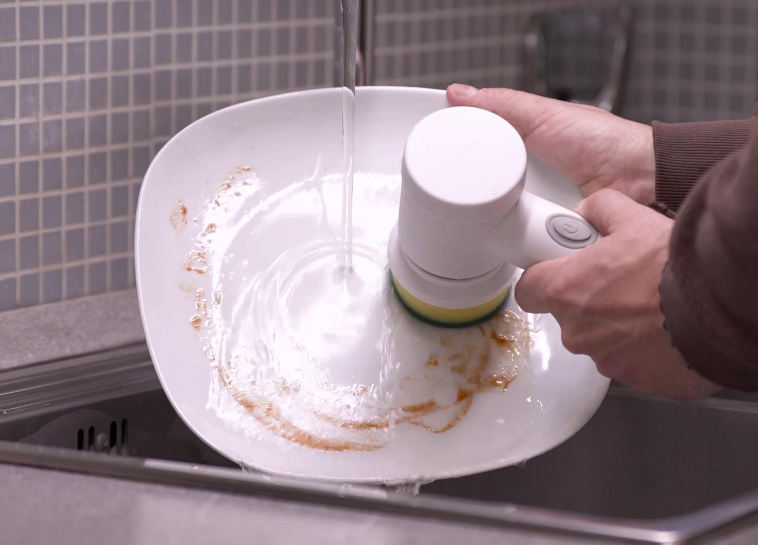 spazzola elettrica rotante mentre pulisce un piatto in cucina
