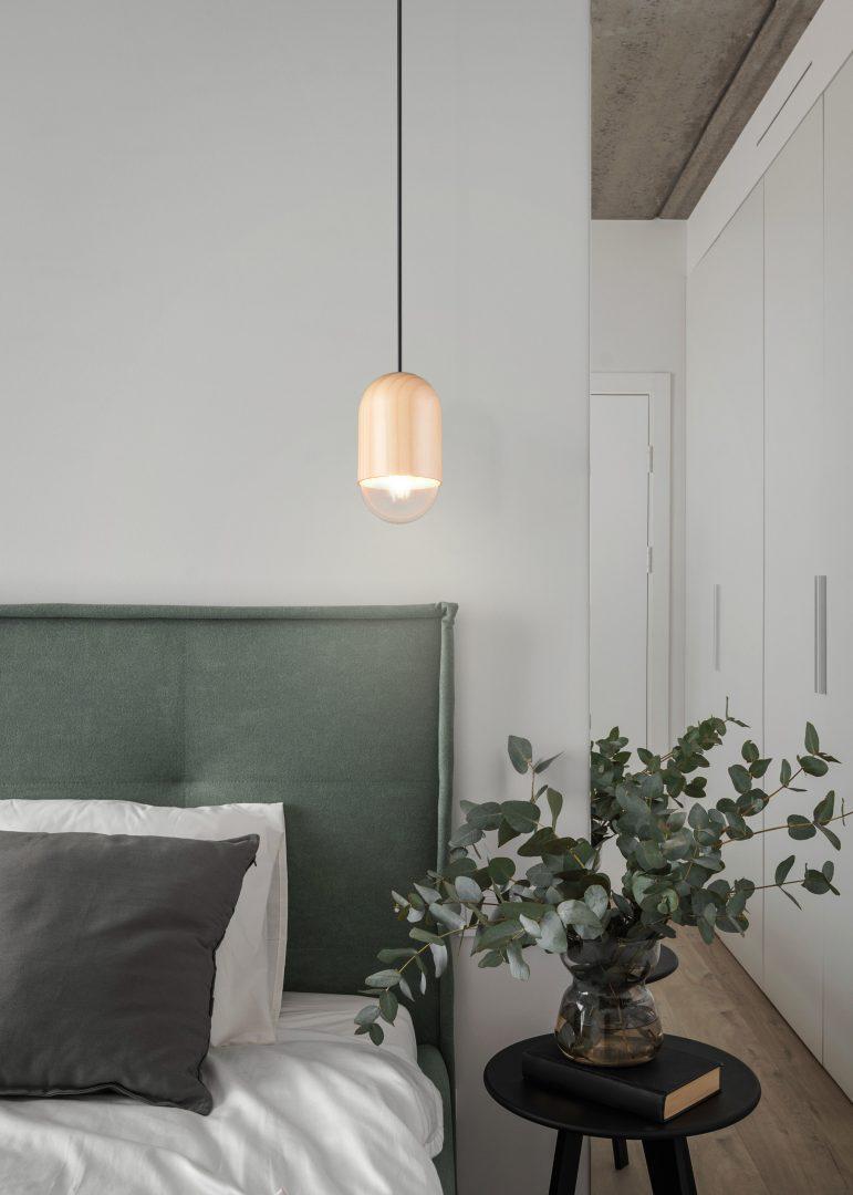 lampada a sospensione installata in camera da letto con arredamento moderno e luce calda