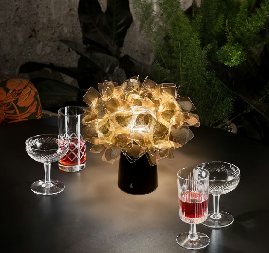 lampada da tavolo slamp clizia battery accesa su tavolo con bicchieri